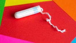 Feminine hygiene tampon on red, pink, orange background, close up 