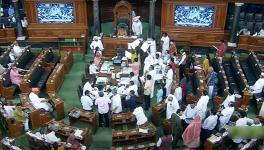 Opposition MPs holding placards stage a protest over inflation, 5% GST on essential items and other issues in the Well of Lok Sabha 