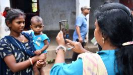 An anganwadi worker taking a photo of a mother named Sikha Sahis, whose photo did not match with her Aadhaar card