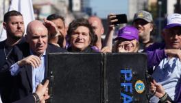 Una maleta es sostenida frente al presidente argentino Javier Milei mientras los manifestantes lanzan botellas y piedras contra el vehículo. Foto: reddit