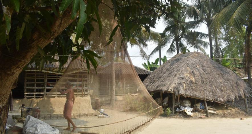A man repairs his fishing net beneath a thatched shelter, a quiet moment of routine (Photo - Raima Kayal, 101Reporters).jpg