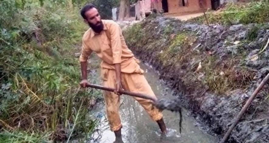 Noorul Shahbaz clears a patch of the canal in his village.