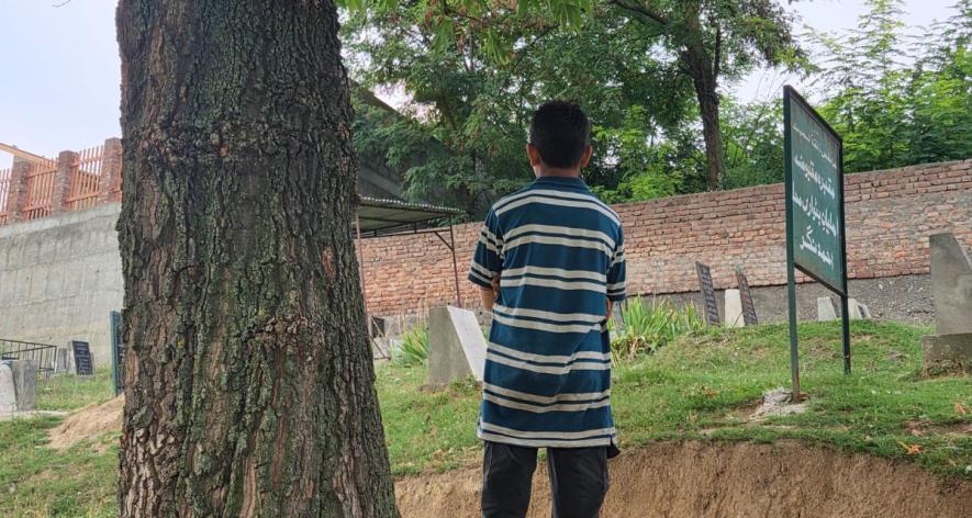 Young boy watches the grave his brother has dug (Photo - Parsa Tariq, 101Reporters).