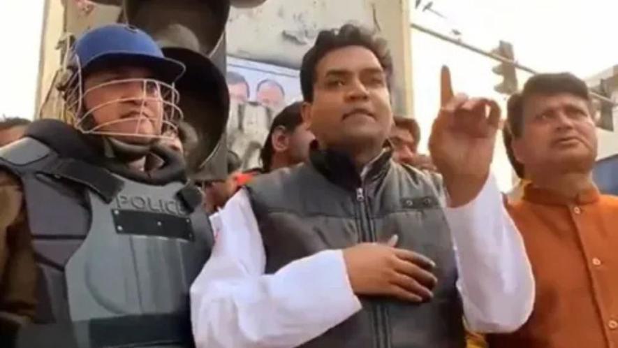 Kapil Mishra speaking at Maujpur, North East Delhi, flanked by Deputy Police Commissioner Ved Prakash Surya in riot gear